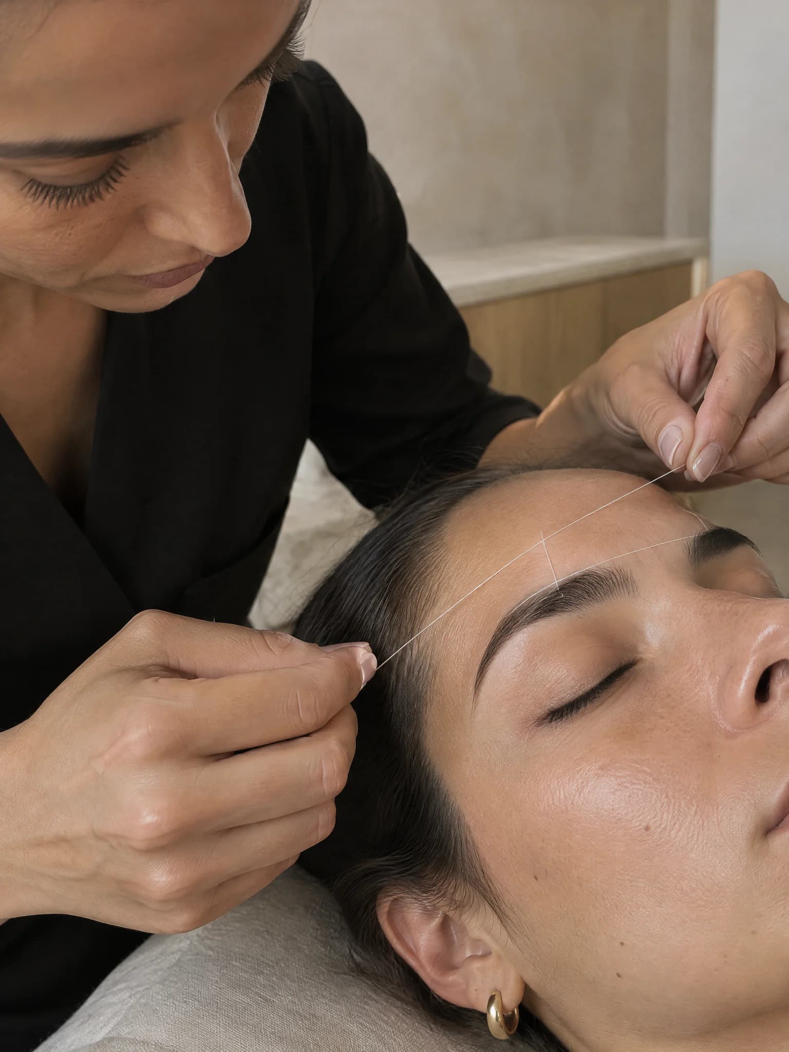 Técnica a modelar uma sobrancelha com linha enquanto a cliente tem os olhos fechados